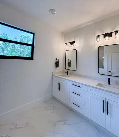Full bathroom featuring double vanity and light marble finish floors
