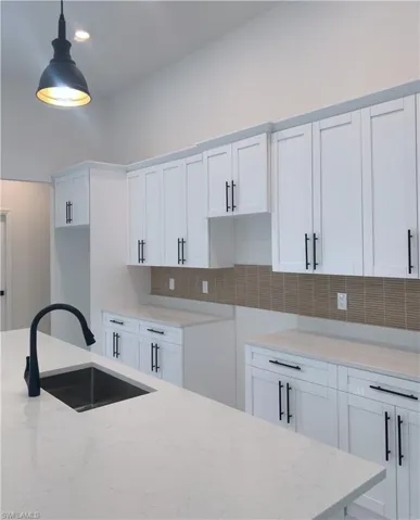 Kitchen featuring white cabinetry, light stone countertops, pendant lighting, tasteful backsplash, and recessed lighting
