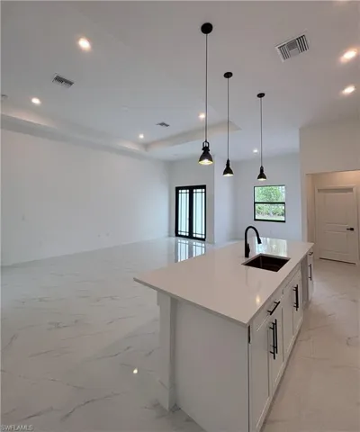 Kitchen with white cabinetry, open floor plan, recessed lighting, light stone counters, and hanging light fixtures