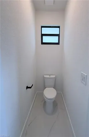 Bathroom with marble finish flooring and a textured wall