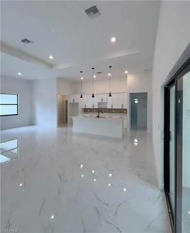 Unfurnished living room featuring recessed lighting, a tray ceiling, and light marble finish flooring