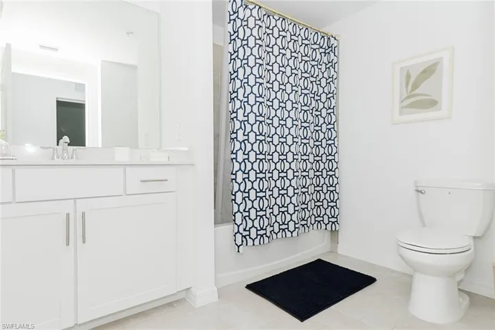 Full bath featuring vanity, shower / bath combination with curtain, and light tile patterned flooring