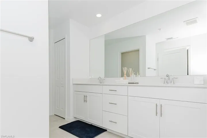 Full bathroom with double vanity, a closet, light tile patterned floors, and recessed lighting