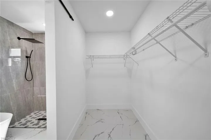 Walk in closet featuring light marble finish floors