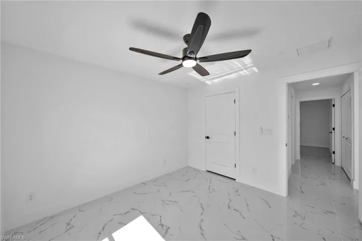 Unfurnished bedroom with a ceiling fan and light marble finish flooring