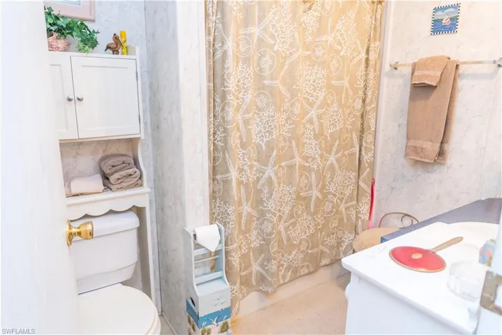 Bathroom with vanity, wallpapered walls, and shower / bath combo