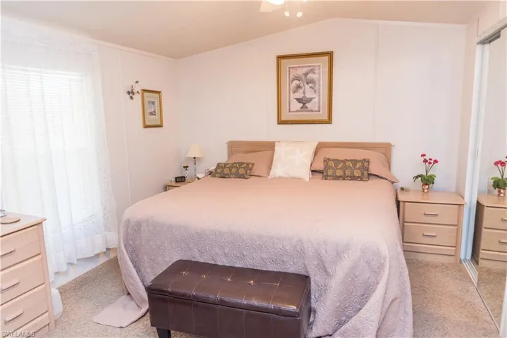 Bedroom with light colored carpet, ceiling fan, and lofted ceiling