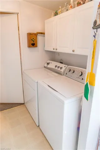 Laundry room with washer and clothes dryer, cabinet space, and light floors