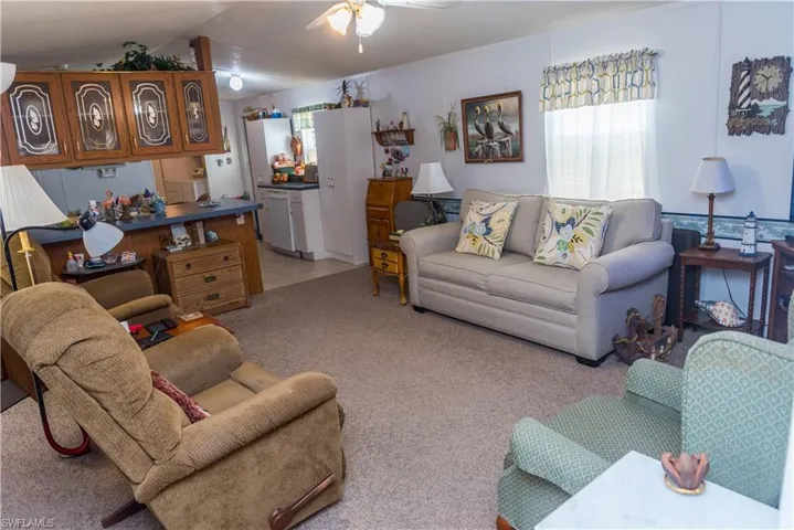 Living area with ceiling fan and light carpet