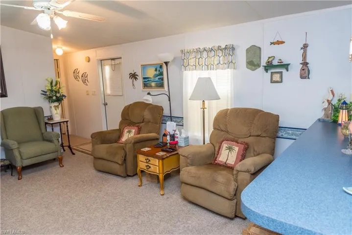 Carpeted living area with ceiling fan