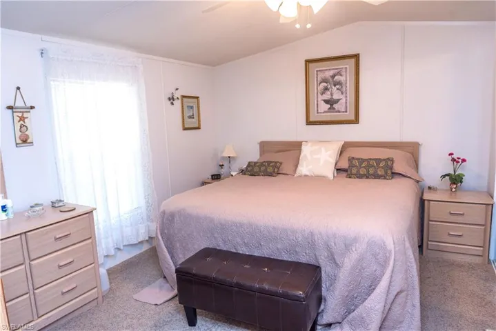 Carpeted bedroom with ceiling fan and vaulted ceiling