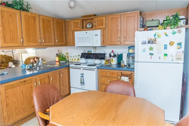 Kitchen with white appliances, wood finish cabinets, and dark countertops