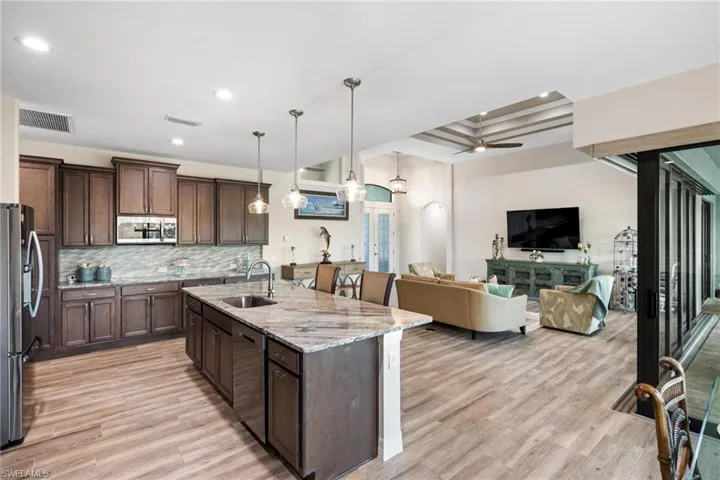 Kitchen featuring sink, stainless steel appliances, decorative light fixtures, and light hardwood / wood-style flooring