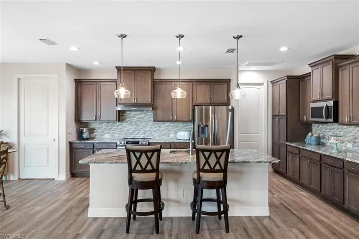 Kitchen featuring hanging light fixtures, light hardwood / wood-style floors, a kitchen island with sink, and appliances with stainless steel finishes