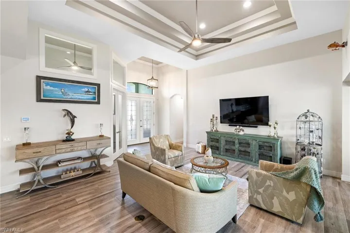 Living room with a raised ceiling, french doors, and hardwood / wood-style flooring