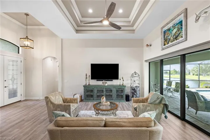 Living room featuring ceiling fan, light hardwood / wood-style floors, ornamental molding, and a high ceiling