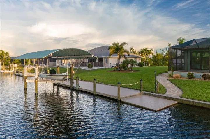 Dock area with a water view, glass enclosure, and a lawn