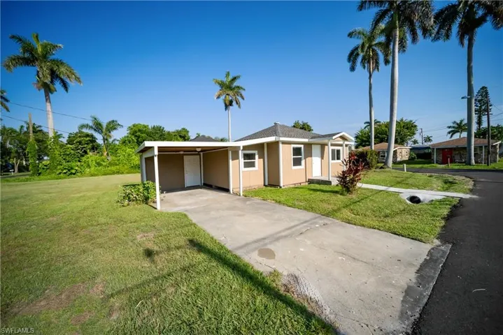 View of front of property featuring a front lawn, driveway, and a carport