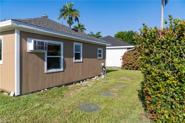 View of property exterior with a yard, roof with shingles, and a wall unit AC