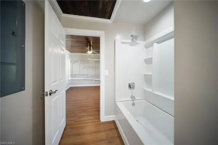 Full bathroom featuring wood finished floors, shower / bathtub combination, baseboards, and ceiling fan