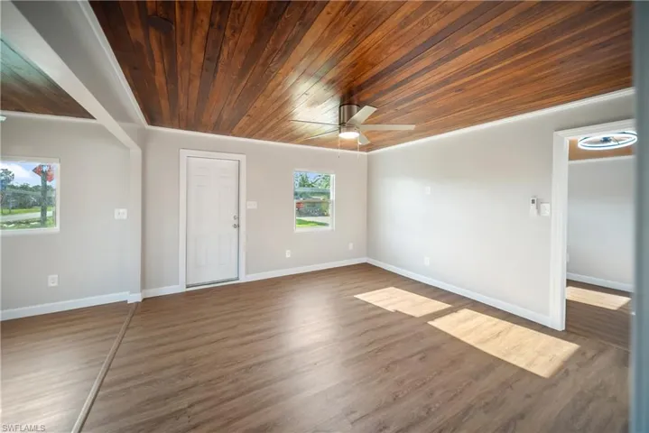 Living room with wood ceiling, ceiling fan, wood finished floors, and baseboards