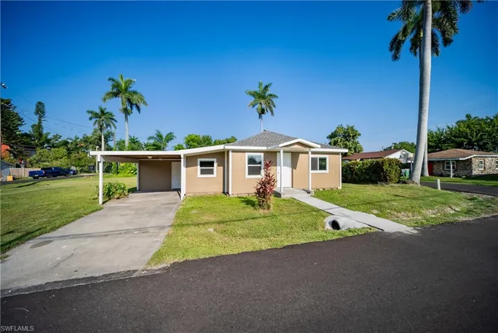 View of front facade with a front lawn, concrete driveway, and a carport