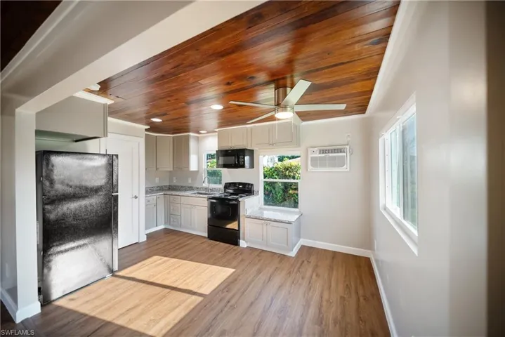 Kitchen with black appliances, wood ceiling, light wood-style flooring, a wall mounted air conditioner, and ceiling fan