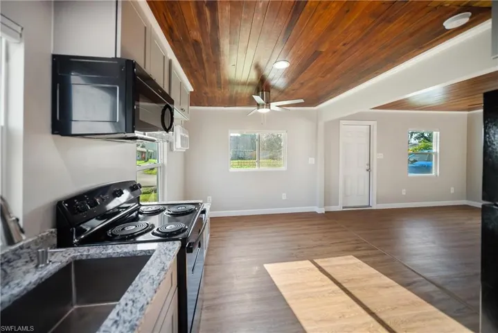 Kitchen with wood ceiling, stainless steel range with electric cooktop, black microwave, a ceiling fan, and healthy amount of natural light