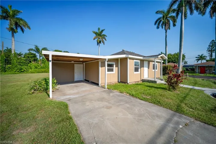 Ranch-style home with a front yard, concrete driveway, and an attached carport