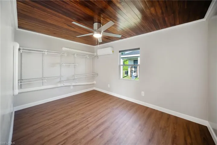 Spare room with an AC wall unit, ceiling fan, baseboards, wooden ceiling, and wood finished floors