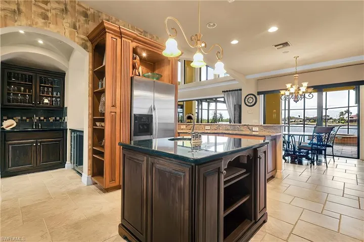 Kitchen with open shelves, dark stone counters, recessed lighting, stainless steel appliances, and a chandelier