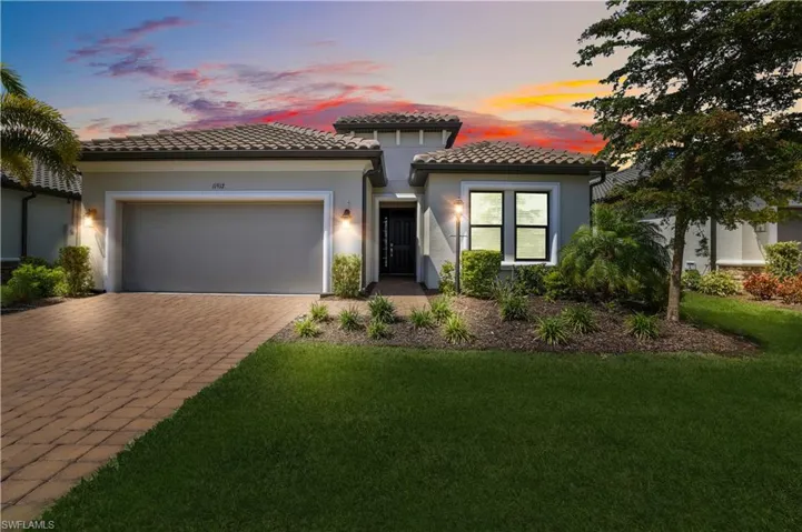 Mediterranean / spanish-style home with a tiled roof, an attached garage, a front yard, stucco siding, and decorative driveway