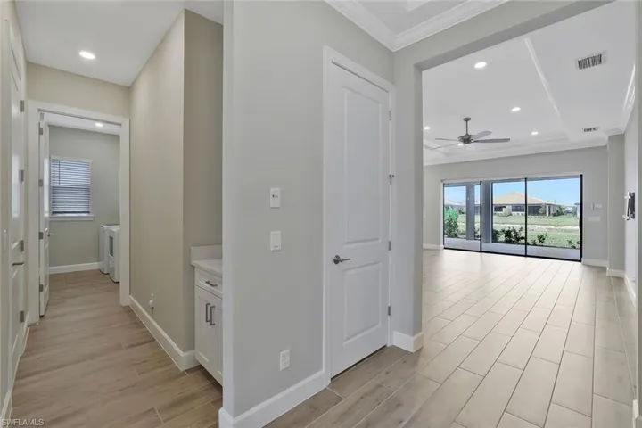 Hallway with separate washer and dryer, baseboards, light wood-style floors, and visible vents