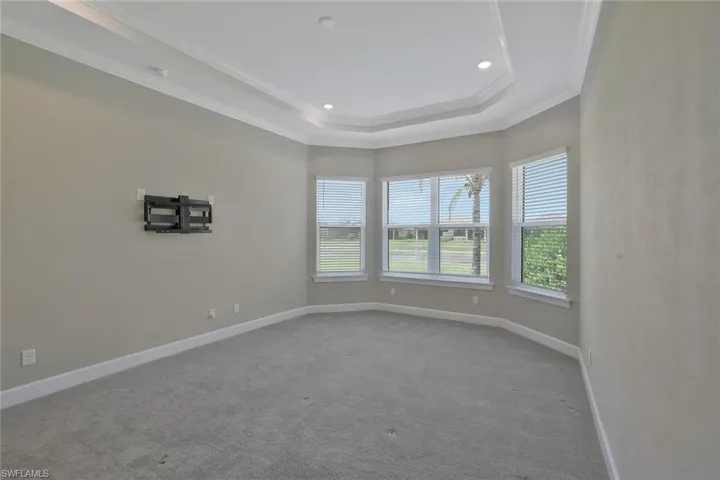 Empty room with crown molding, carpet, a raised ceiling, baseboards, and recessed lighting