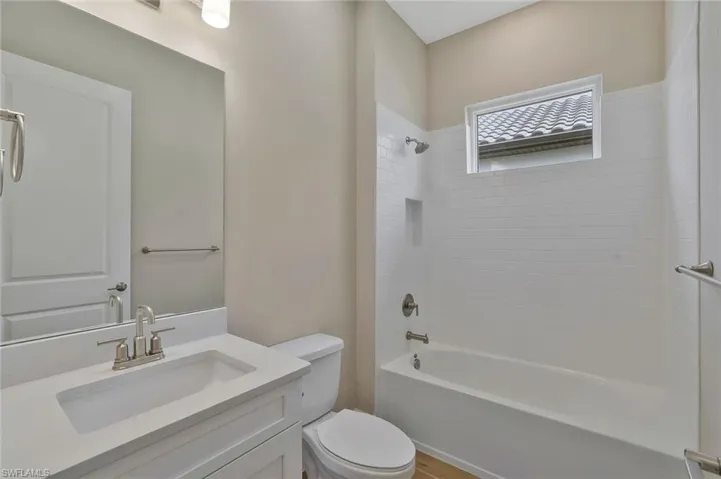 Bathroom with shower / washtub combination, wood finished floors, vanity, and toilet