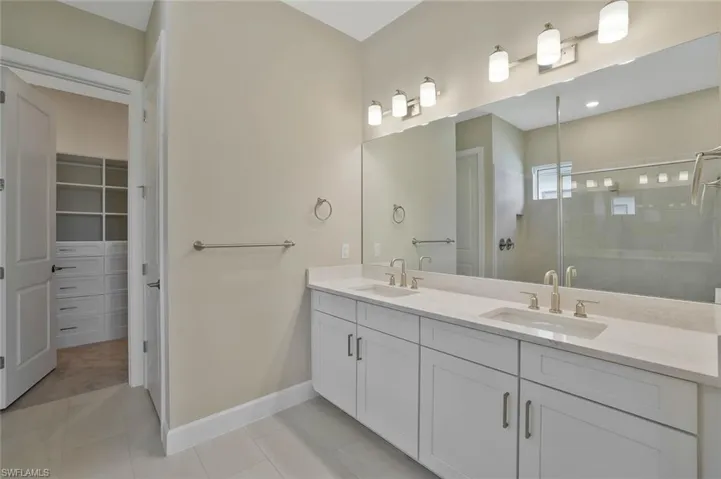 Bathroom with tile patterned flooring, a sink, double vanity, and a stall shower