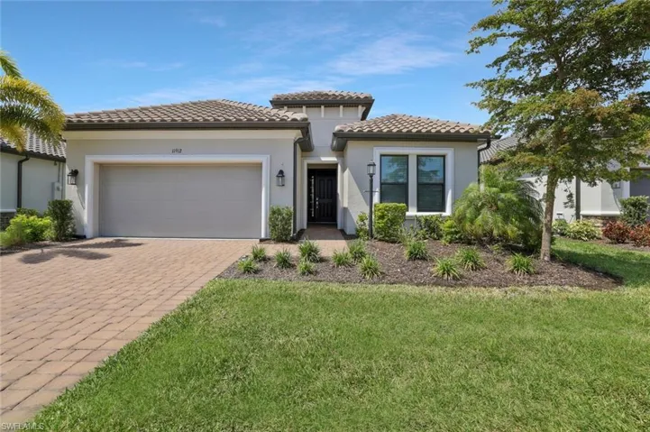 Mediterranean / spanish-style home featuring a tiled roof, driveway, a garage, a front yard, and stucco siding