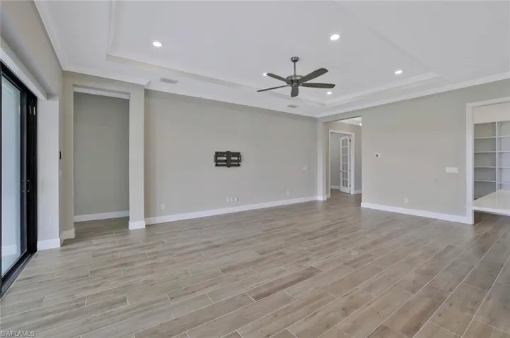 Spare room featuring a tray ceiling, crown molding, light wood-style floors, and a ceiling fan