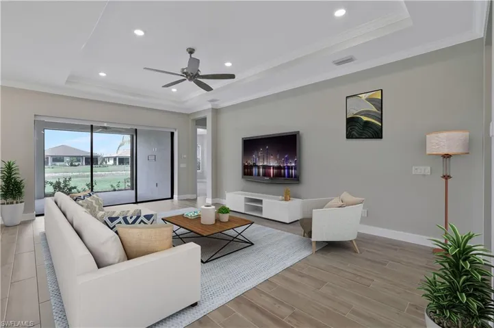 Living area with ornamental molding, baseboards, a tray ceiling, and ceiling fan