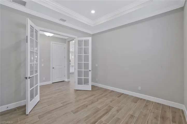Unfurnished room featuring baseboards, visible vents, french doors, and light wood finished floors