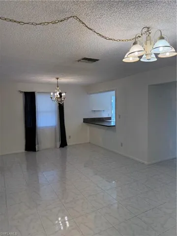Empty room with hanging lights and a textured ceiling