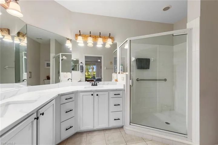 Full bathroom featuring double vanity, a shower stall, and light tile patterned floors