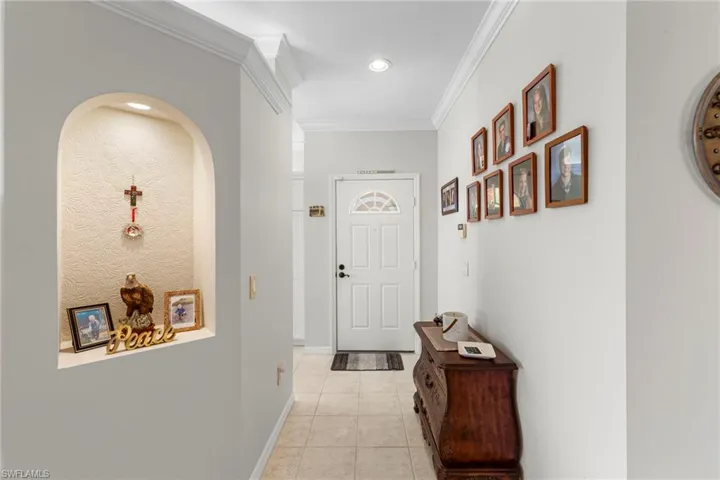 Hallway with ornamental molding, light tile patterned floors, and recessed lighting