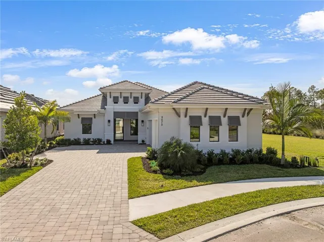 View of front facade with decorative driveway, stucco siding, a front lawn, and a tile roof