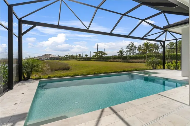 View of pool featuring a sunroom, glass enclosure, a yard, a patio area, and a pool with connected hot tub