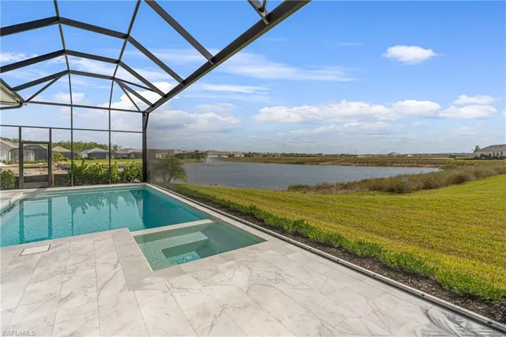 View of pool featuring a sunroom, a lawn, glass enclosure, and a pool with connected hot tub
