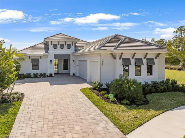 Prairie-style home with stucco siding, decorative driveway, a garage, a front lawn, and a tile roof