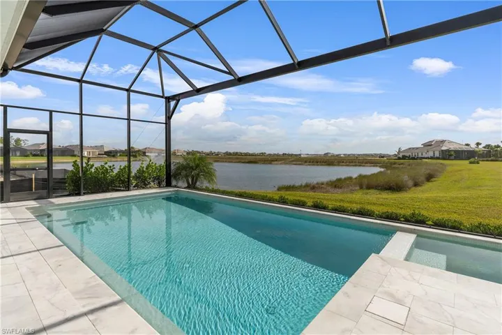 View of pool featuring a lanai, a sunroom, a water view, a lawn, and a pool with connected hot tub