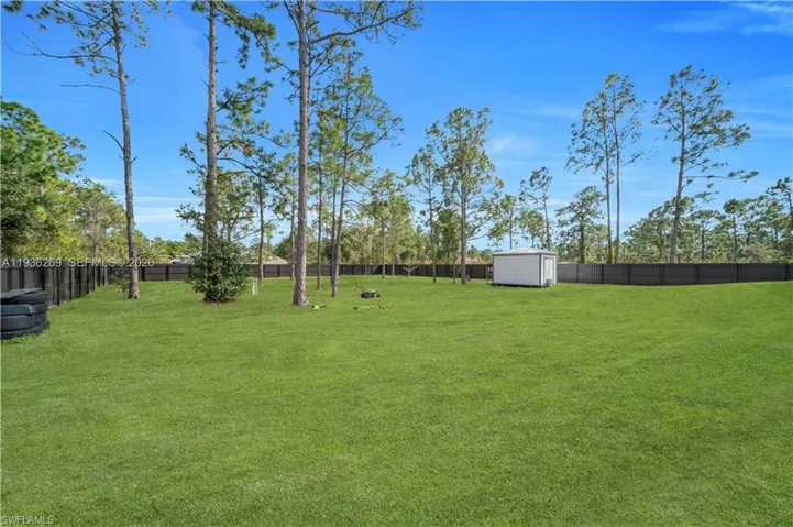 Fenced backyard featuring a storage unit