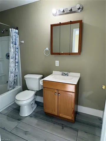 Bathroom featuring wood-finish vanity with white countertop and integrated sink, recessed medicine cabinet with mirror, modern light fixture, and tile flooring